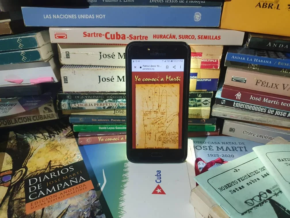 A book displayed on a phone among printed books about Cuban history and culture
